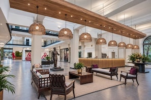 A spacious lobby with a high ceiling, multiple hanging pendant lights, a reception desk, seating area, and a statue. - Mandela Rhodes Sky Suite I Mountain & Pool Views (Cape Town)