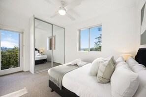 Quarto com cama, espelho grande e vista da cidade.
