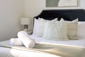 A neatly made bed with white linens and a rolled towel, a black upholstered headboard, and a bedside lamp. - Modern 2BR Apt Near Eastwood, Top Ryde and Transport (Ryde)