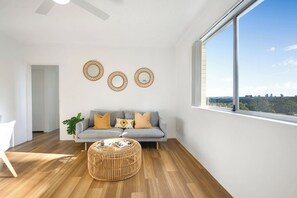 A modern living room with a grey sofa, a round wicker ottoman, and three wall-mounted mirrors. - Modern 2BR Apt Near Eastwood, Top Ryde and Transport (Ryde)