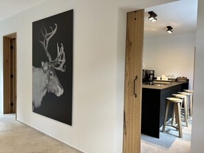 A modern kitchen with a central island, bar stools, and a large black and white deer artwork on the wall. - Romantic Cabin Winterberg-willingen (Medebach)