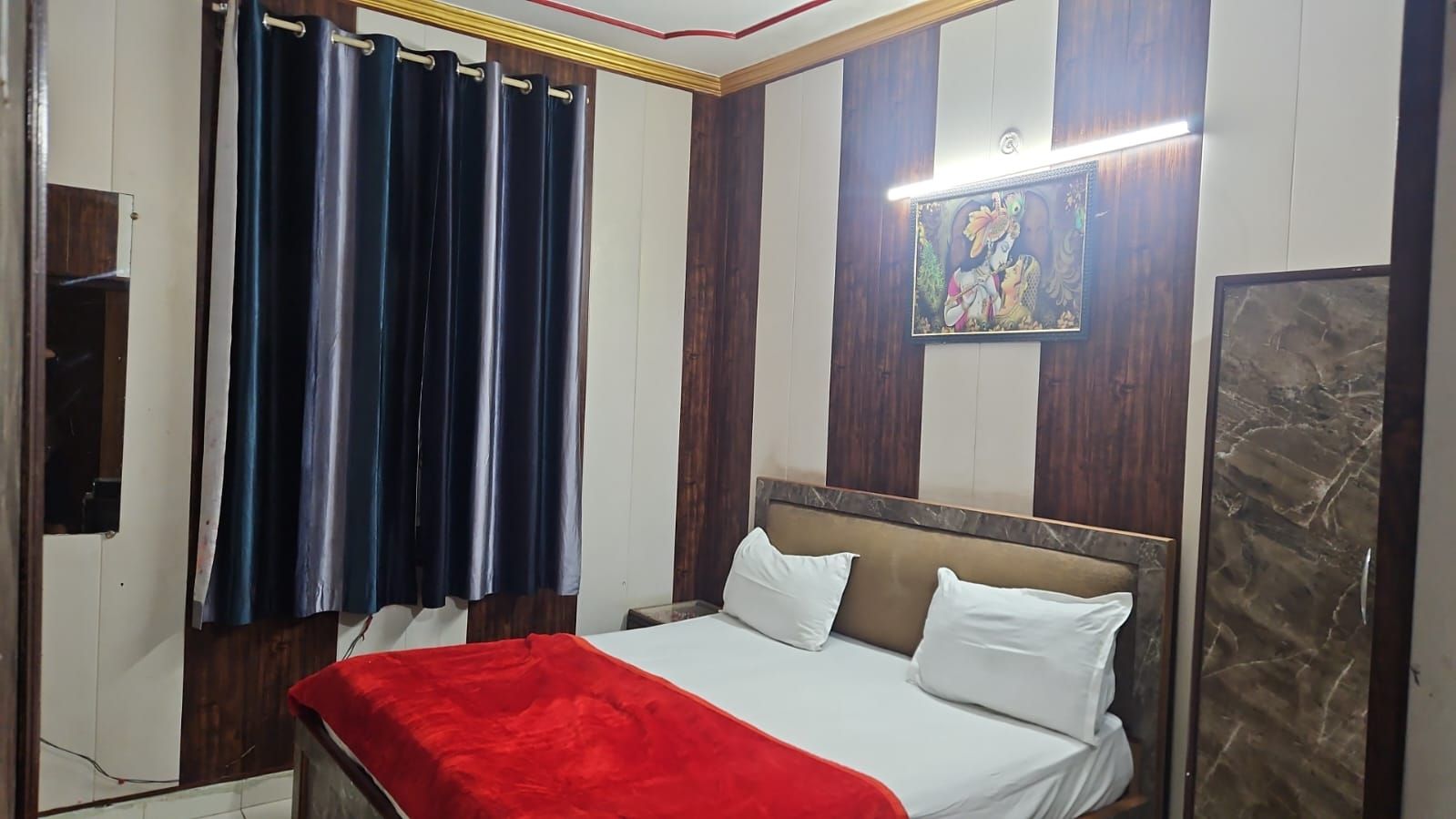Un dormitorio con cama, cortinas, un cuadro y un espejo.