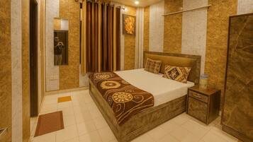 Una habitación de hotel con cama, mesita de noche, espejo y puerta.