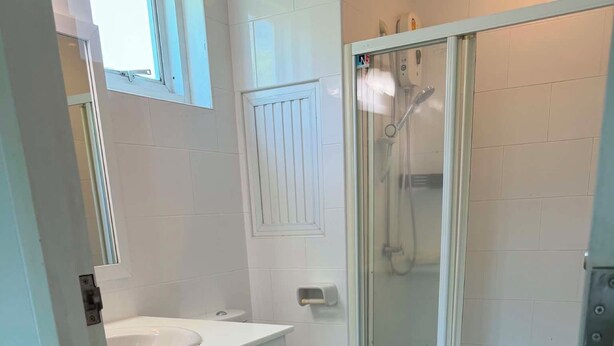 Une salle de bain avec douche, toilettes et lavabo.