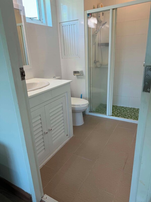 Ein Badezimmer mit Dusche, Toilette und Waschtisch.