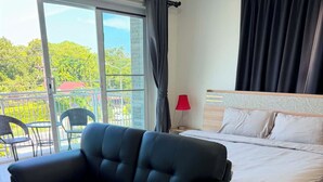 Une chambre moderne avec un canapé, un lit et une vue sur la verdure environnante.