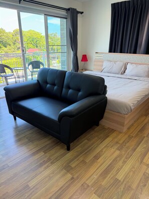 Ein modernes Schlafzimmer mit Sofa, Bett und Blick auf Grünflächen.