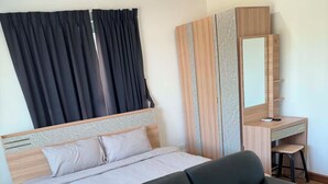 Une chambre à coucher moderne avec un lit, un canapé noir, un bureau en bois et un miroir.