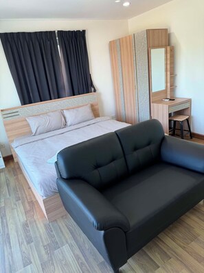 Ein modernes Schlafzimmer mit einem Bett, einer schwarzen Couch, einem Holztisch und einem Spiegel.