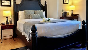 A hotel room with a large bed, a nightstand with a lamp, a bedside table, and a framed picture on the wall. - Water View 1BR near Brown & RISD, Parking + Elevator (Providence)