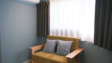 Quarto com um sofá, uma janela com cortinas e um aparelho de ar condicionado.