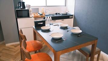 A modern kitchen with a dining table, chairs, and various kitchen appliances.