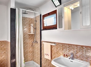 A bathroom with a shower, a sink, and a mirror. - Il Frantoio (Massa Lubrense)