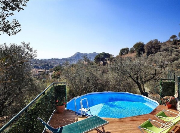 An outdoor swimming pool with a wooden deck, surrounded by trees and a mountain view. - Il Frantoio (Massa Lubrense)