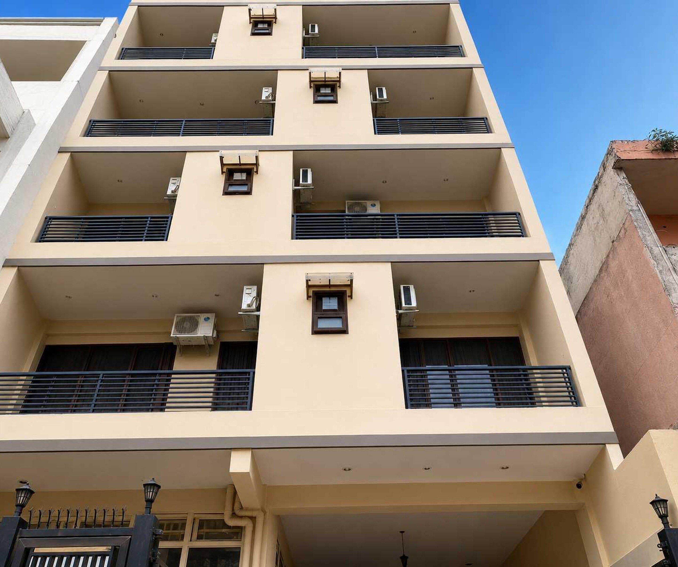 A multi-story building with balconies, air conditioning units, and a gated entrance.
