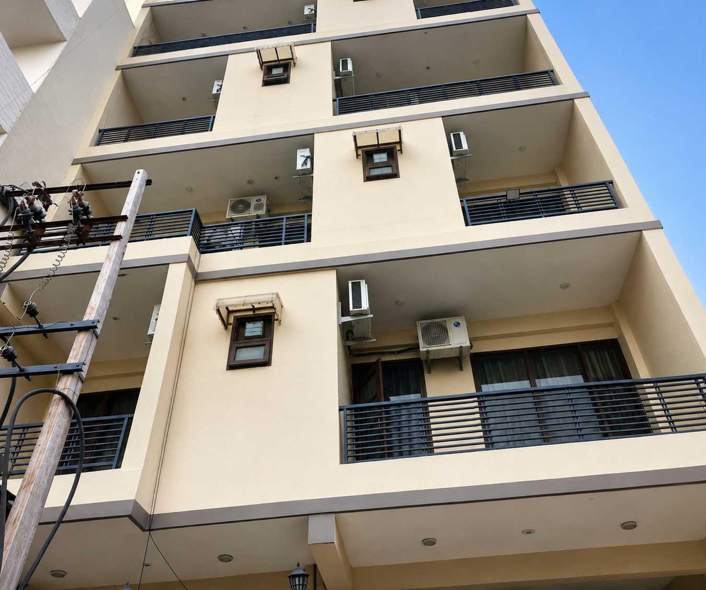 A multi-story building with balconies, air conditioning units, and visible electrical infrastructure.