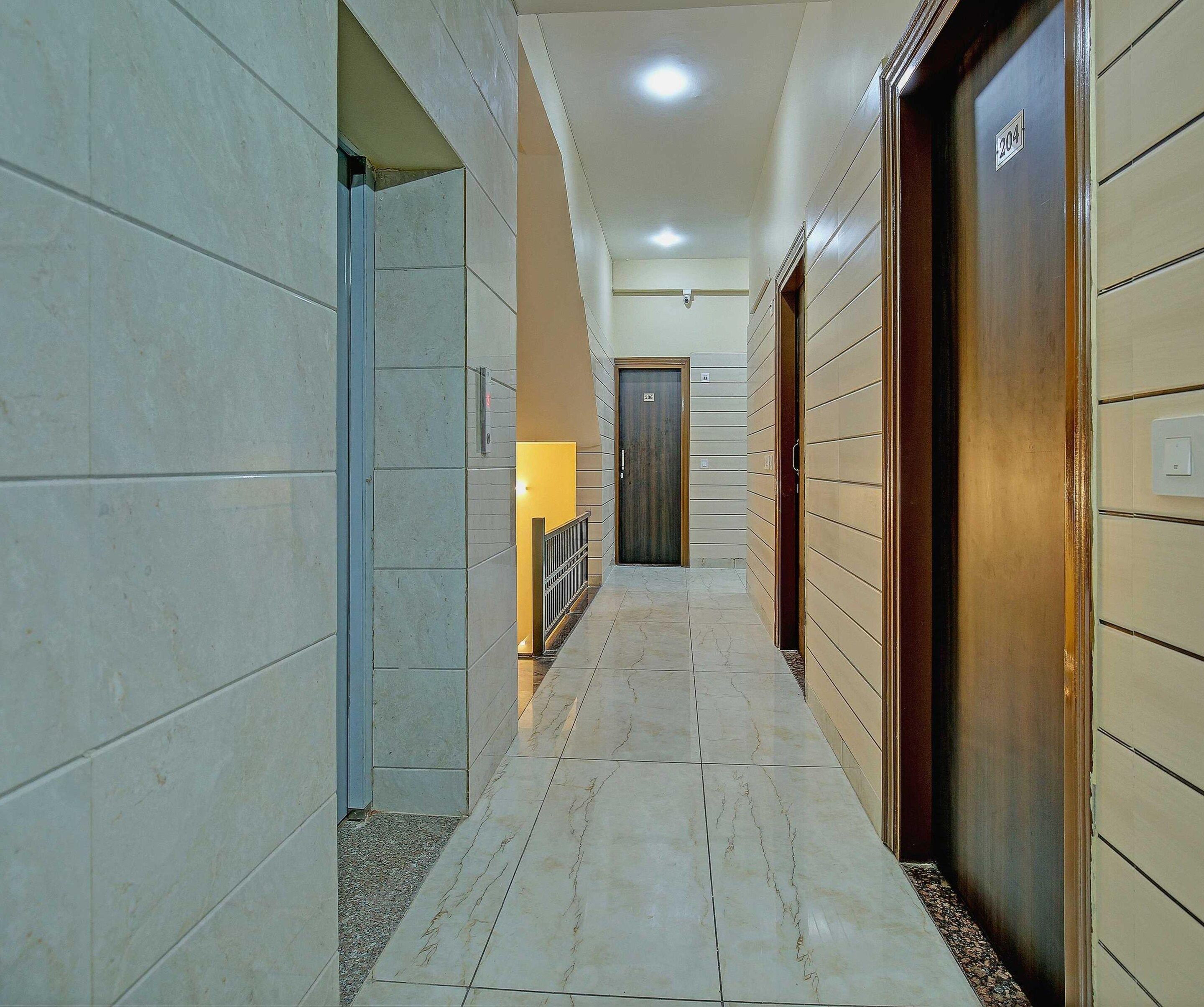 A hallway with a tiled floor, a door with a number, and a light fixture.