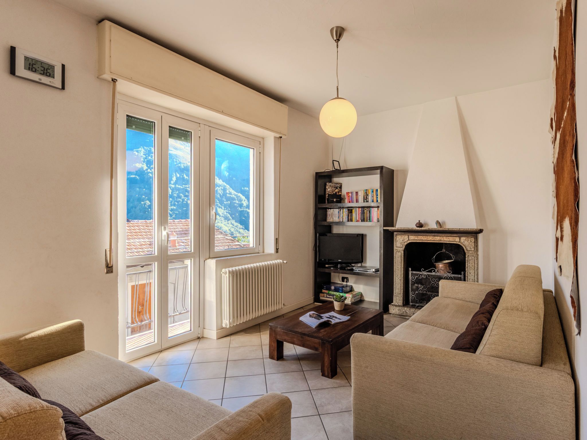 A living room with a fireplace, a bookshelf, and a view of the outdoors.