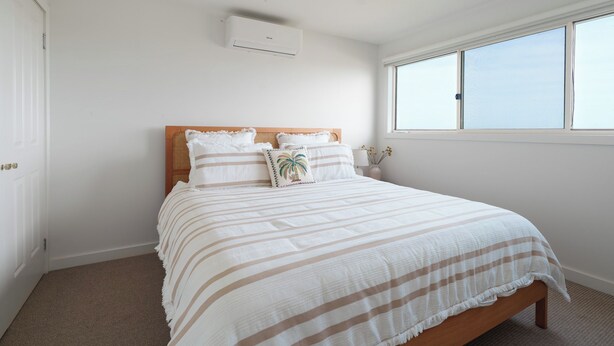 Une chambre à coucher avec un lit, un ventilateur de plafond, une fenêtre et un appareil de climatisation.