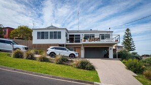 Une maison moderne à deux étages, dotée d’un garage, d’une allée et d’une pelouse bien entretenue.