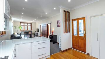 A modern kitchen with white cabinetry, a dining area with a table and chairs, and a wooden floor.