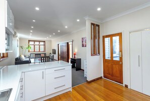 A modern kitchen with white cabinetry, a dining area with a table and chairs, and a wooden floor. - Masterton central, fully renovated character Villa (Masterton)