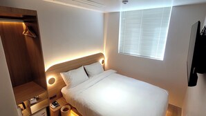 Un dormitorio moderno con cama, mesita de noche y una pequeña silla de madera.