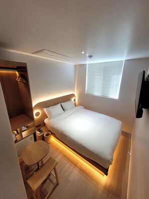 Une chambre à coucher moderne avec un lit, une table de chevet et une petite chaise en bois.