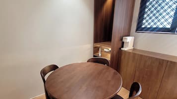 A dining area with a round wooden table and four chairs, a built-in wooden cabinet, and a window with a lattice design.