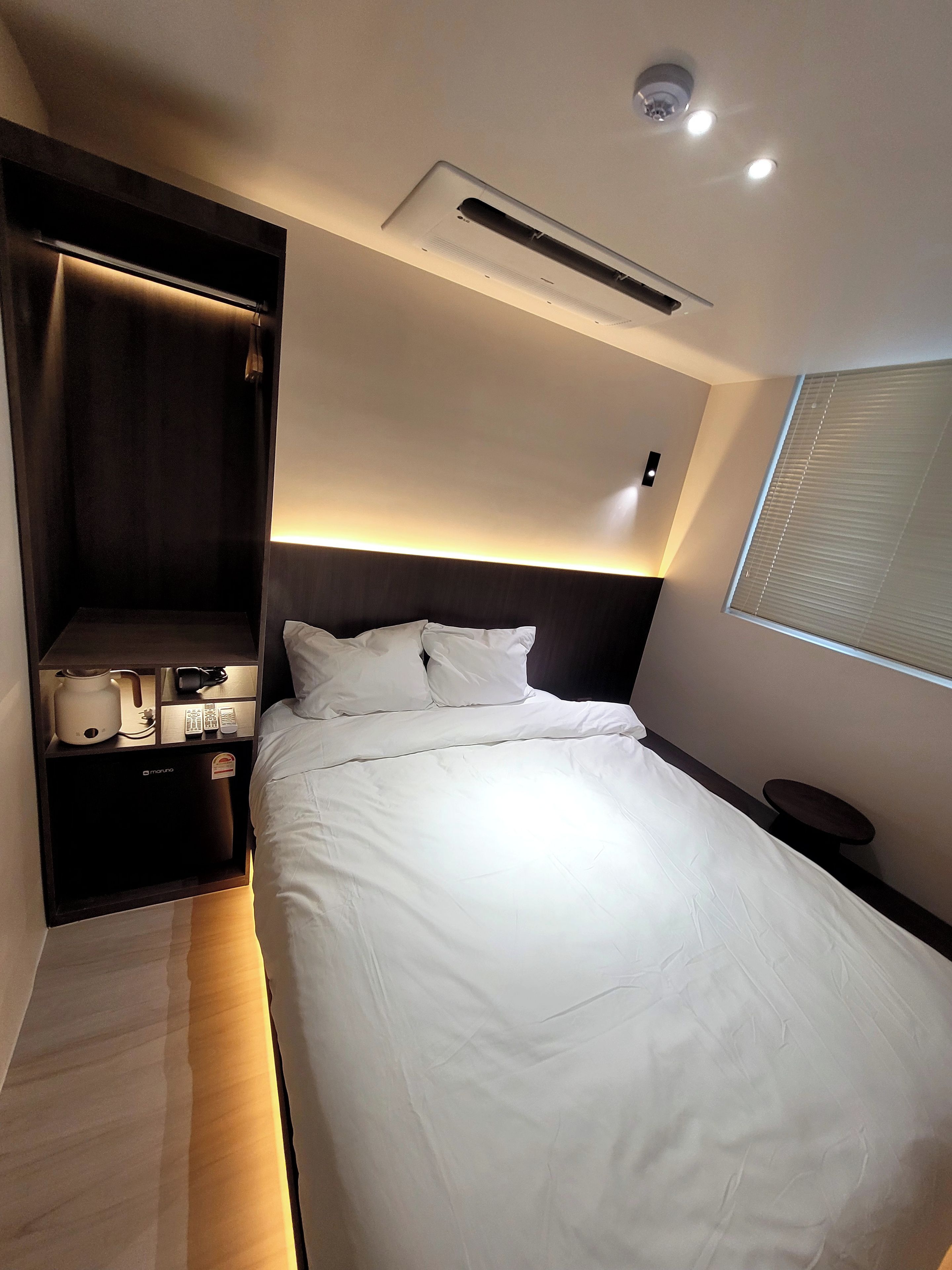 Una habitación de hotel con cama, mesita de noche y armario empotrado.