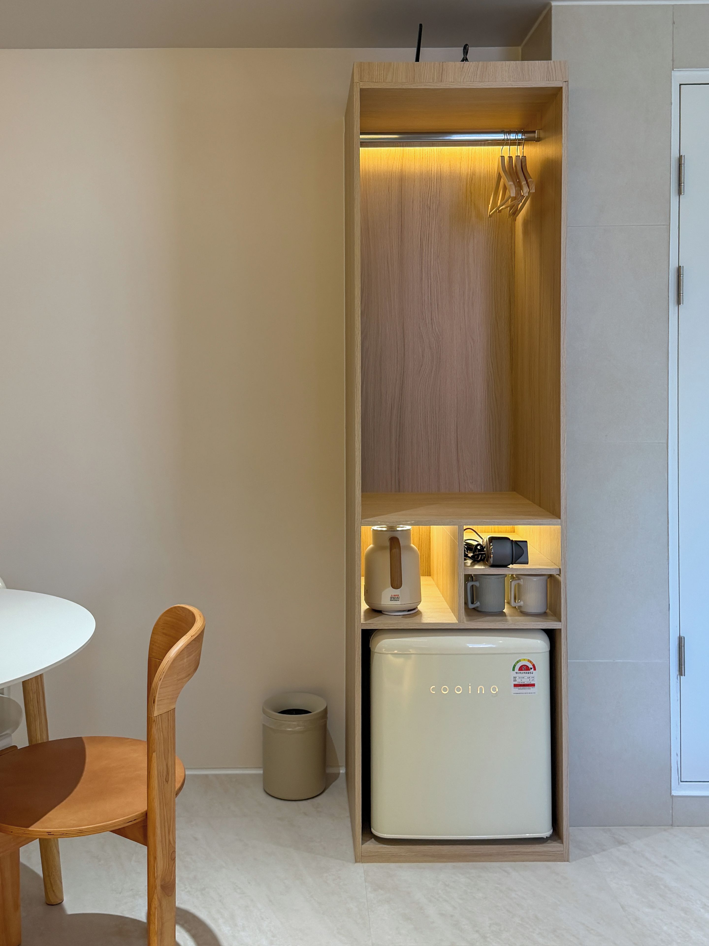 A compact kitchenette with a built-in refrigerator, a kettle, and a microwave.