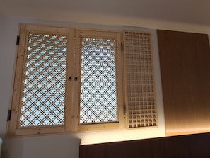 A room with a wooden door with a lattice design, a wooden panel wall, and a wooden cabinet.
