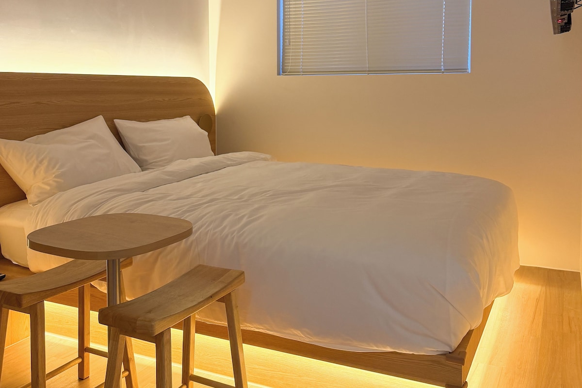 A hotel room with a bed, a small round table, and a TV mounted on the wall.