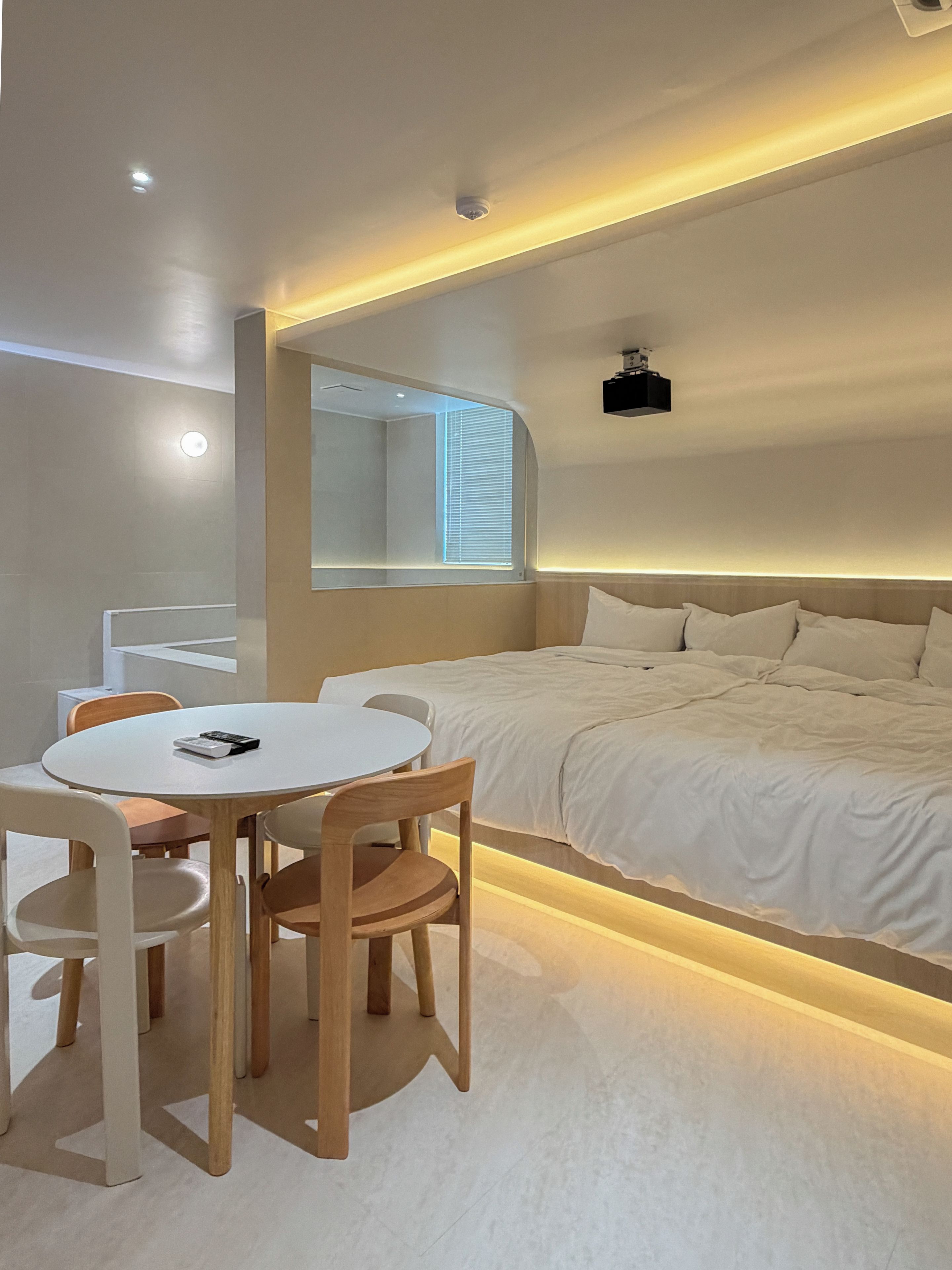 A modern bedroom with a bed, a round table, and chairs.