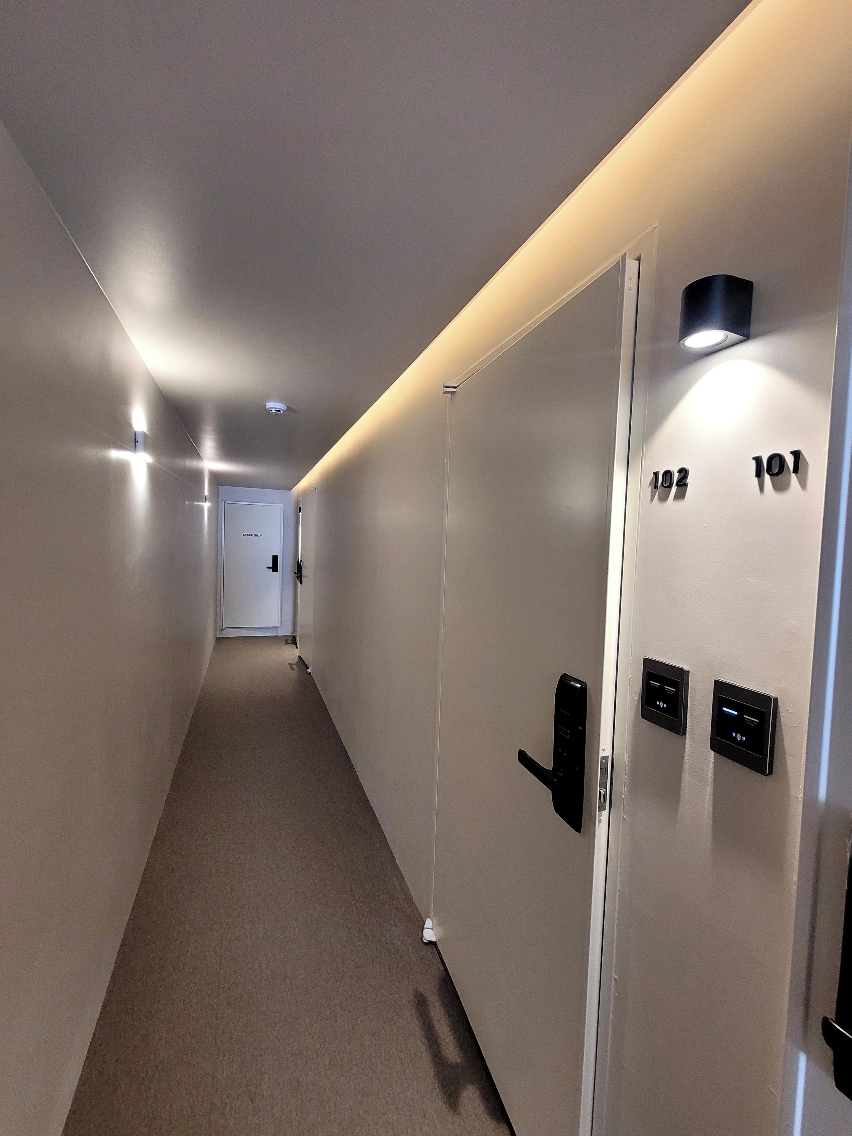 A hallway with doors numbered 102 and 101, a 'staff only' sign, and a light fixture on the ceiling.