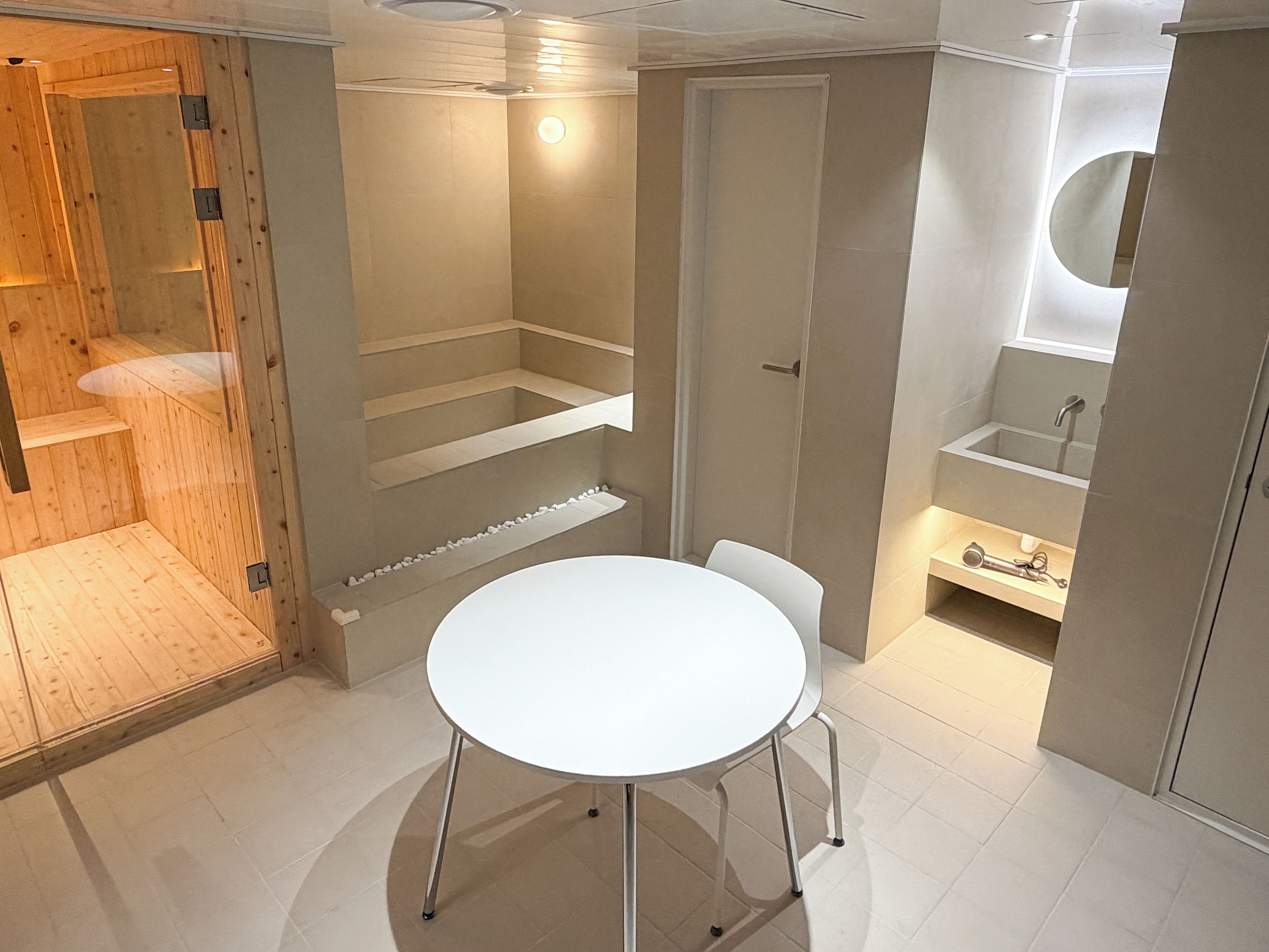 A modern bathroom with a white sink, a mirror, and a shower area.