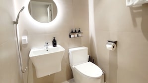 Un baño moderno con inodoro, lavamanos y ducha.