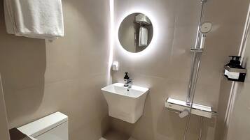 A modern bathroom with a toilet, sink, and shower.