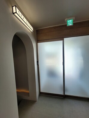 A hallway with a spa sign, a green emergency exit sign, and a sliding glass door.