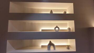 Three white shelves with various ceramic objects.