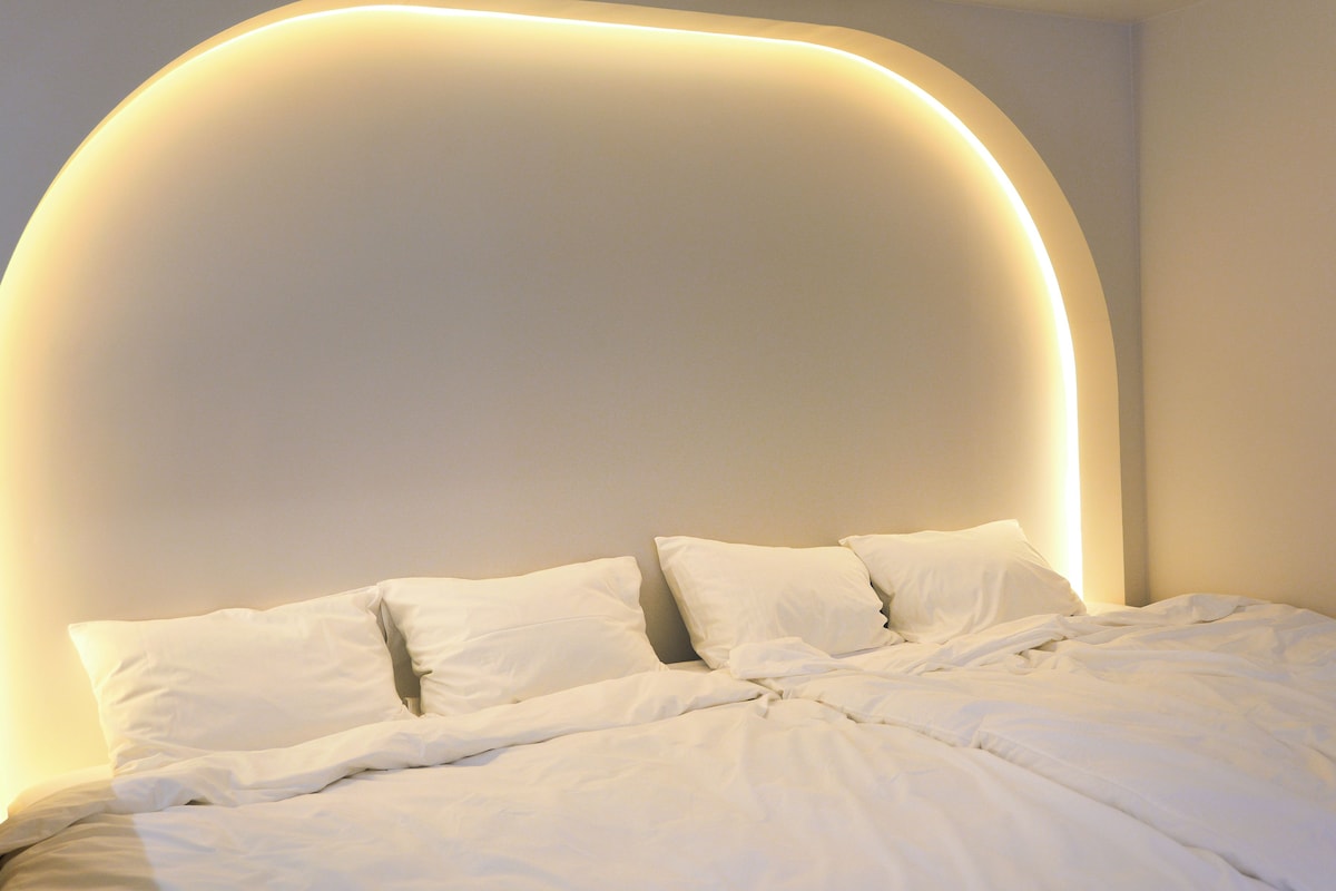 A bed with white bedding and pillows, a curved wall, and a soft light source.