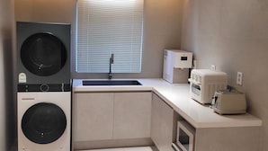 Una cocina compacta con espacio para relajarse, lavadora, microondas y tostadora.