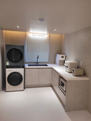 Une cuisine compacte avec un coin salon, un lave-linge, un four à micro-ondes et un grille-pain.