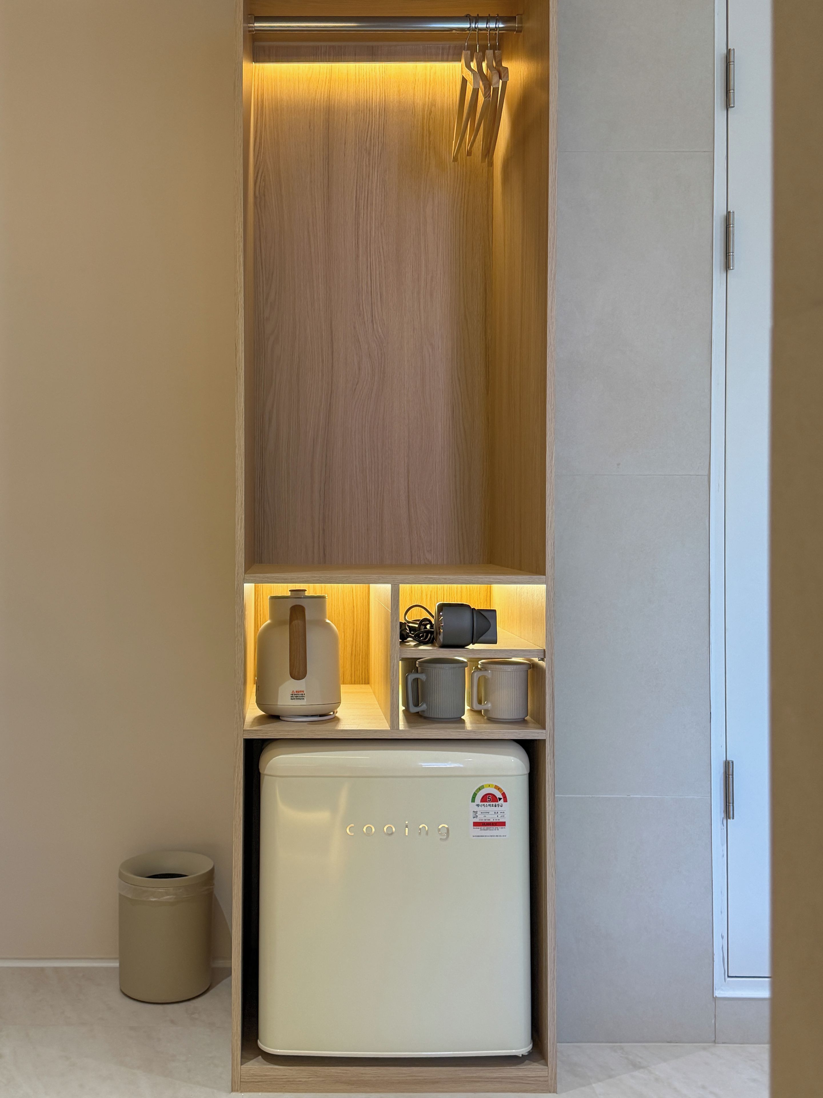 A compact kitchenette with a built-in refrigerator, a kettle, and a coffee maker.