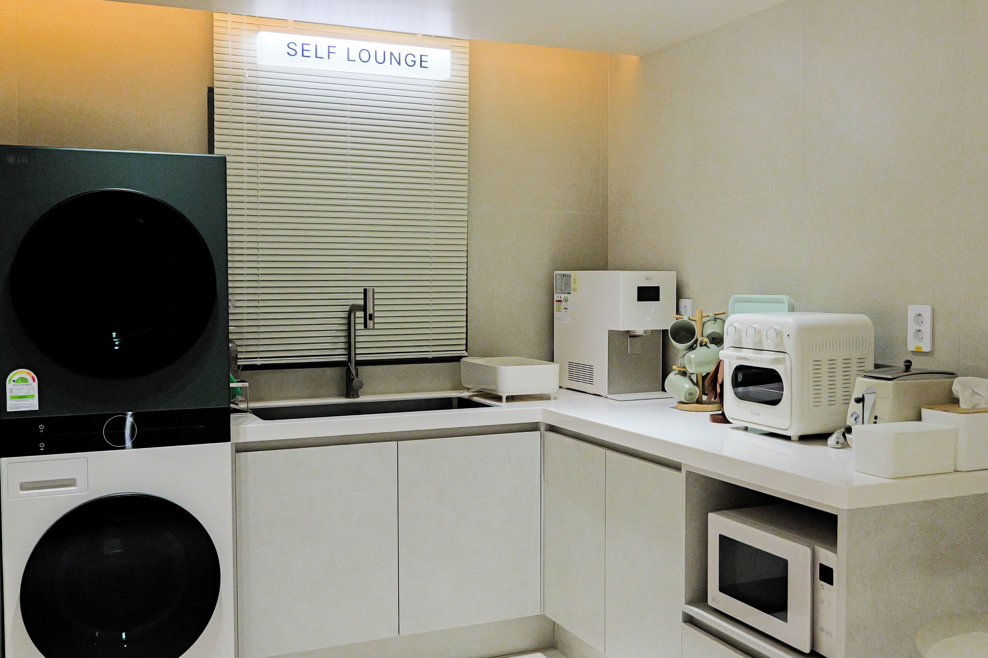 A self-service lounge with a washing machine, microwave, and coffee maker.