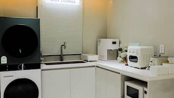 A self-service lounge with a washing machine, microwave, and coffee maker.