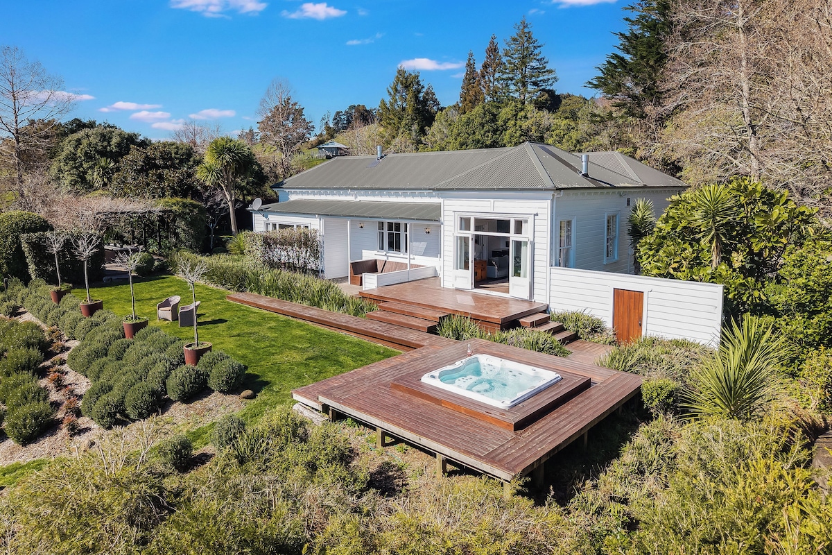 A modern house with a deck, a hot tub, and a well-maintained garden.