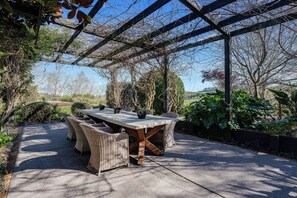 An outdoor patio with a table and chairs, surrounded by greenery and a pergola structure. - The An Chroi Estate by Homello (Bombay)
