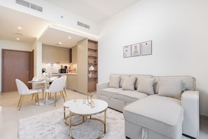 A modern living room with a grey sofa, a round coffee table, and a dining area with a white table and chairs. - Vogue | VYB at Business Bay close to Downtown (Dubai)