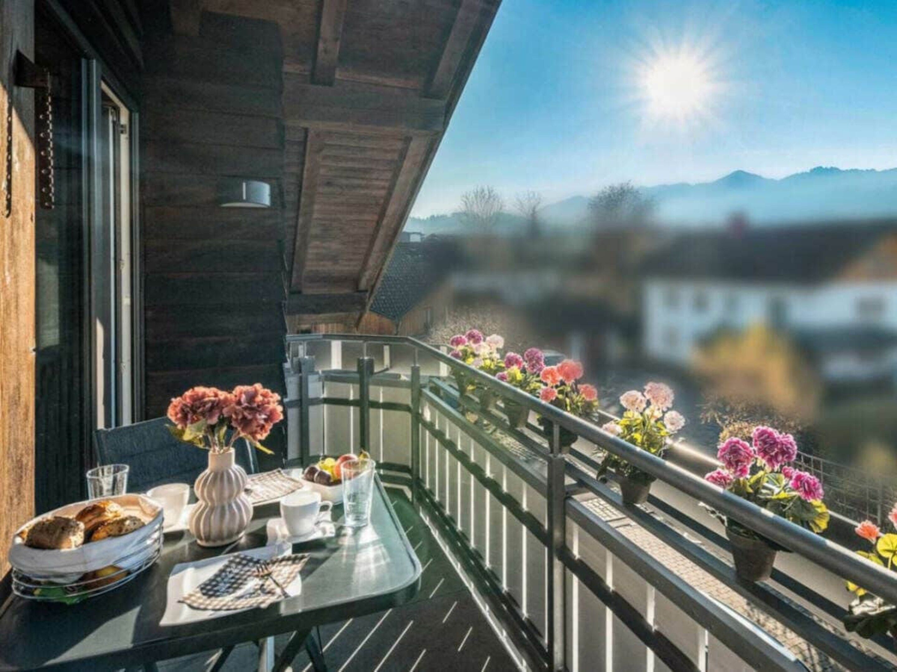 A balcony with a table set for breakfast, overlooking a mountainous landscape.